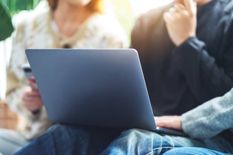 A group of people using and looking at the same laptop computer during a meeting
